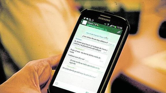 Una mujer lee en el WhatsApp los mensajes del grupo de padres de la clase de su hijo. 