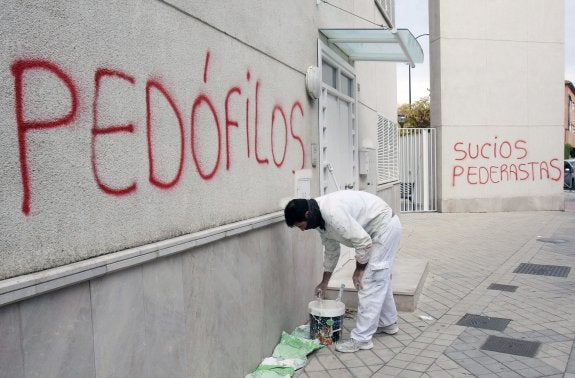 Un pintor comienza a ocultar las pintadas aparecidas en las paredes de la parroquia San Juan María Vianney de Granada. 