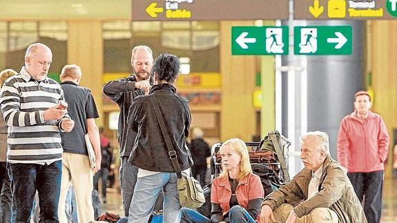 Turistas esperan en la terminal del aeropuerto para facturar sus equipajes.