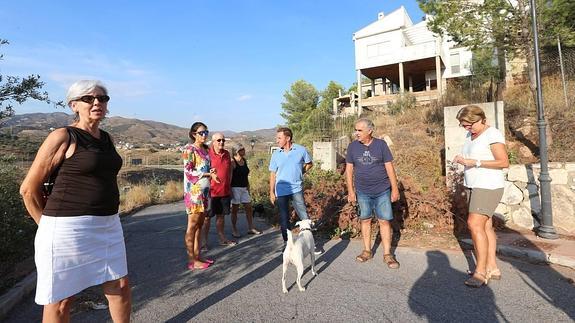Algunos de los propietarios y familiares afectados de la urbanización, con las casas demolidas al fondo.