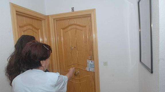 Una vecina señala la puerta de la vivienda de la víctima, precintada por la policía. 