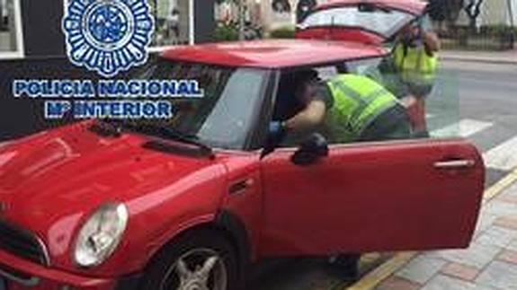 Un agente inspecciona el coche que usaba uno de los arrestados.