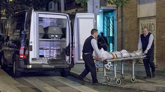 Los servicios funerarios trasladan el cadáver de la mujer fallecida.