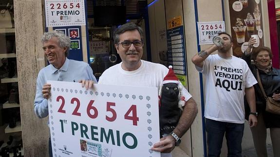 Miguel Ángel Jiménez, a la derecha, sostiene el cartel anunciando el premio y la figura del gato negro, que es el emblema de su administración.