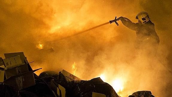 Un bombero sofoca las llamas en unos contenedores de la calle Comandante Román. 