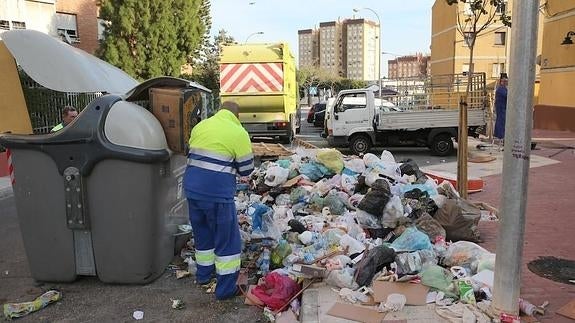 Operarios de Limasa retiran la basura acumulada en la calle Torrox, en Portada Alta