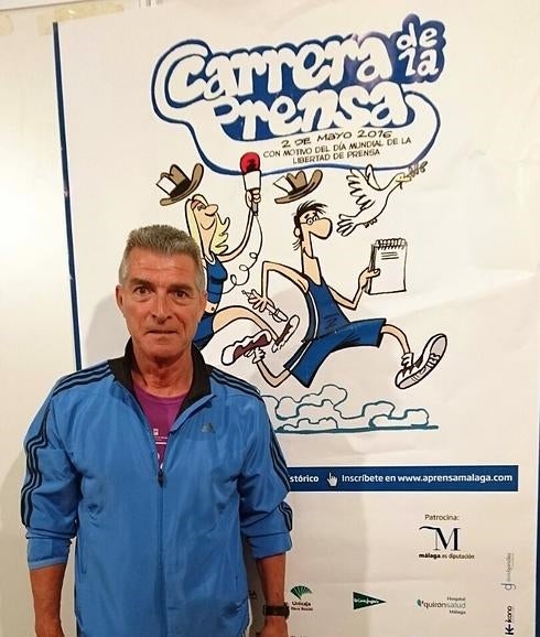 Manolo Sarria posa con el cartel de la carrera detrás. 