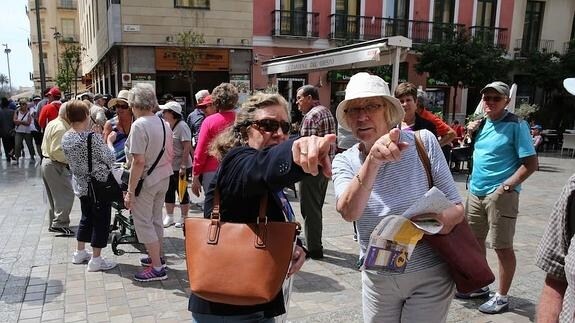 Una turista extranjera recibe indicaciones para seguir su visita turística a Málaga.