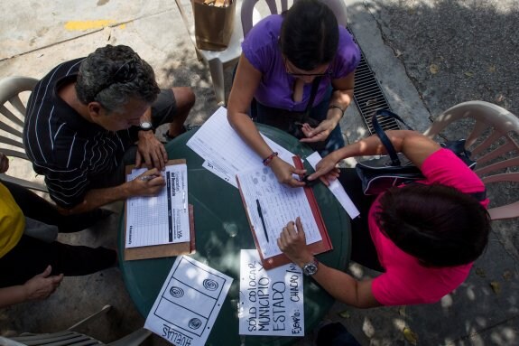 Unas personas firman en el listado para pedir el referendo. :: efe