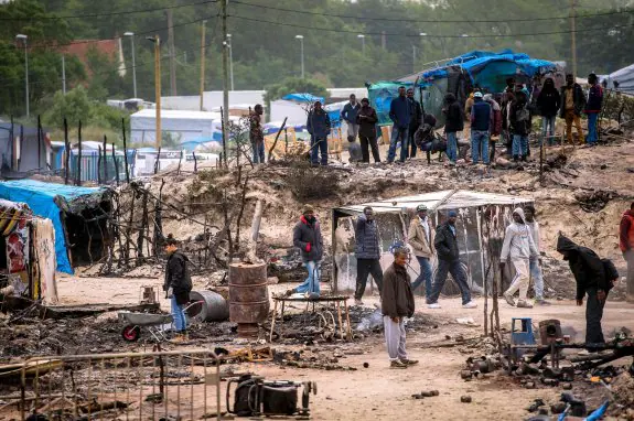 Un grupo de refugiados rebusca entre los restos de las chabolas quemadas en el campamento de 'La Jungla', en Calais. :: PHILIPPE HUGUEN / Afp