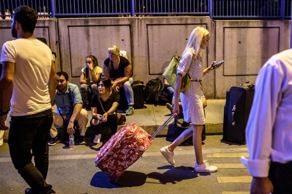 Algunos pasajeros esperan noticias con sus equipajes en los exteriores del aeropuerto Atatürk de Estambul. :: OZAN KOSE / afp
