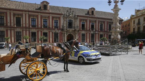 Un coche de caballos y una patrulla policial junto a una de las tribunas, en la Plaza de la Virgen de los Reyes, que estaban preparadas para la visita del presidente de EEUU. 