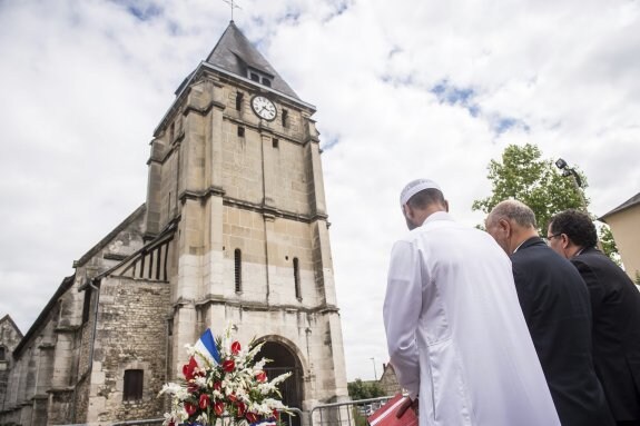 Varios musulmanes mantienen un minuto de silencio en memoria del sacerdote Jacques Hamel ante la iglesia donde fue degollado. :: efe