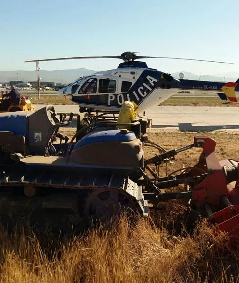 Una de las máquinas de desbroce, junto al helicóptero del Cuerpo Nacional de Policía.