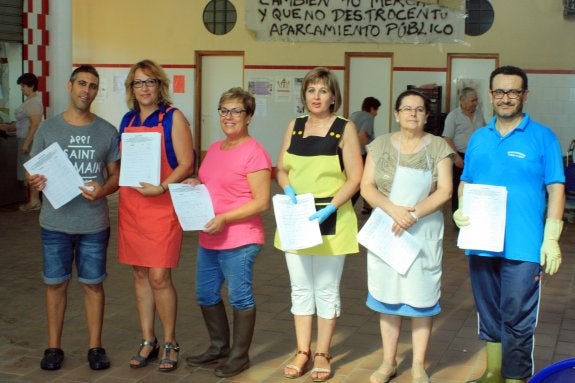 Tenderos del mercado de abastos muestran algunas de las firmas recogidas. 