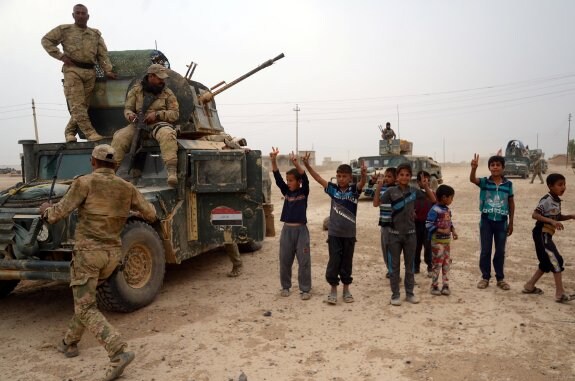 Unos niños saludan a una caravana del Ejército en Al-Shura, al sur de Mosul, en manos del EI. :: Reuters