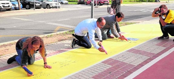 Algunas personas dejando su huella en el poema gigante. A la derecha, detalle de un escrito.  :: crónica / p. hérvele