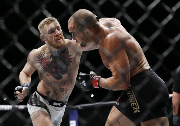McGregor con sus cinturones y, abajo, en combate. :: Usa Today