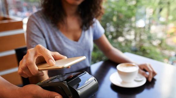 Una mujer usa su teléfono móvil para pagar la comida en un restaurante. 