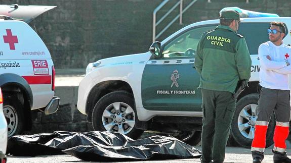 Agentes de la Guardia Civil y de Cruz Roja en el puerto de Algeciras, con uno de los cinco cadáveres de inmigrantes que han sido encontrados.