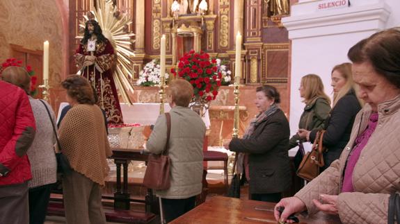 Una mujer deposita las monedas ante el Cristo de Medinaceli, esta mañana en la iglesia del Cristo de la Salud.