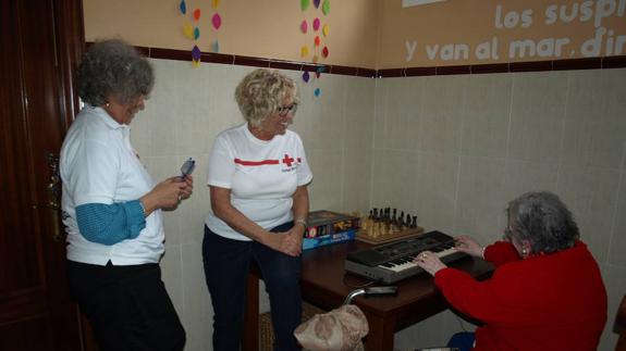 Las voluntarias Auxiliadora Romero y María Baena escuchan a una de las residentes de Los Milagros mientras toca el órgano.