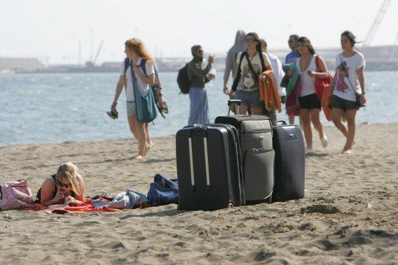 Turistas, con equipajes preparados, aprovechan hasta el último momento la playa. 