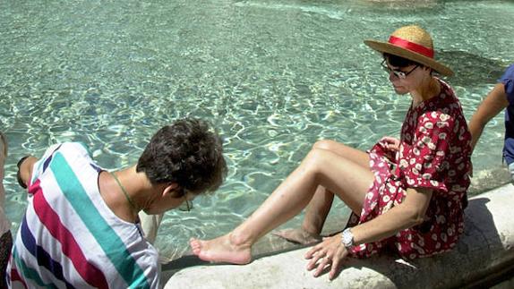 Dos turistas ponen los pies a remojo en la Fontana de Trevi. 