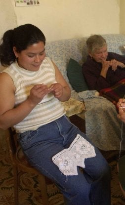 Una inmigrante cose junto a una anciana. / SUR