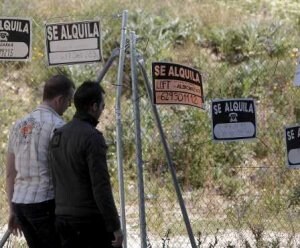 Dos jóvenes pasan junto a una valla repleta de carteles de 'Se alquila'. ::
SUR