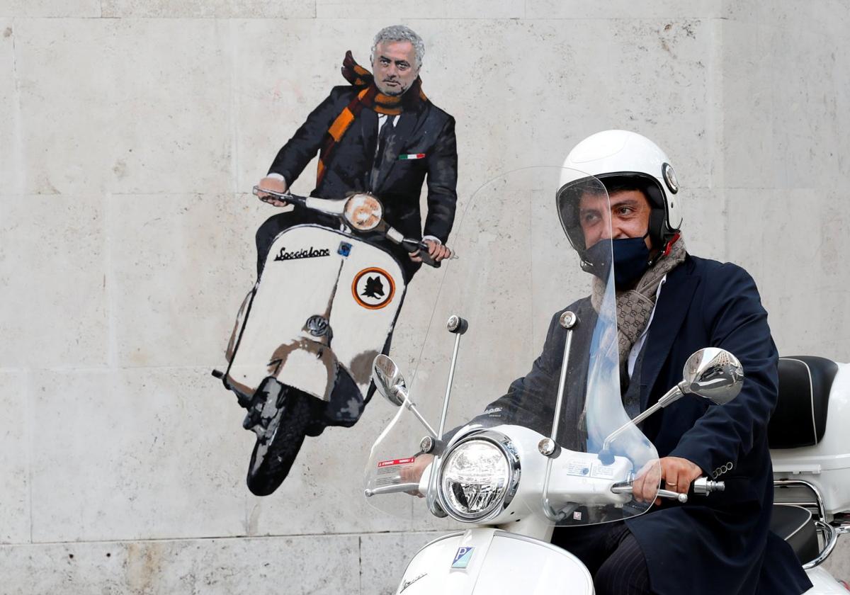 Un motorista pasa ante un grafiti de Mourinho a los mandos de una Vespa en el barrio de Testaccioen Roma.