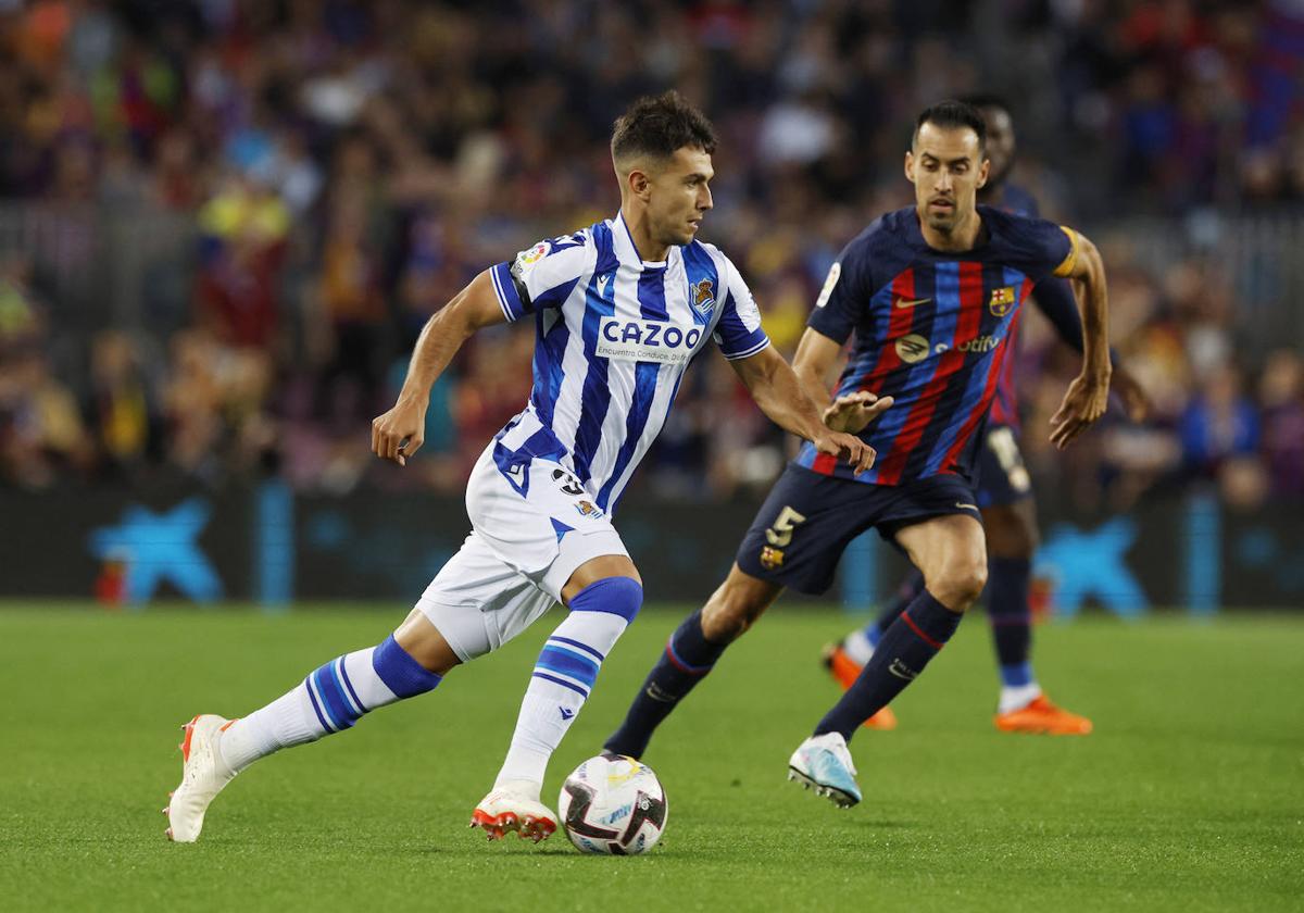 Martín Zubimendi avanza con el balón ante Sergi Busquets durante el Barcelona - Real Sociedad.
