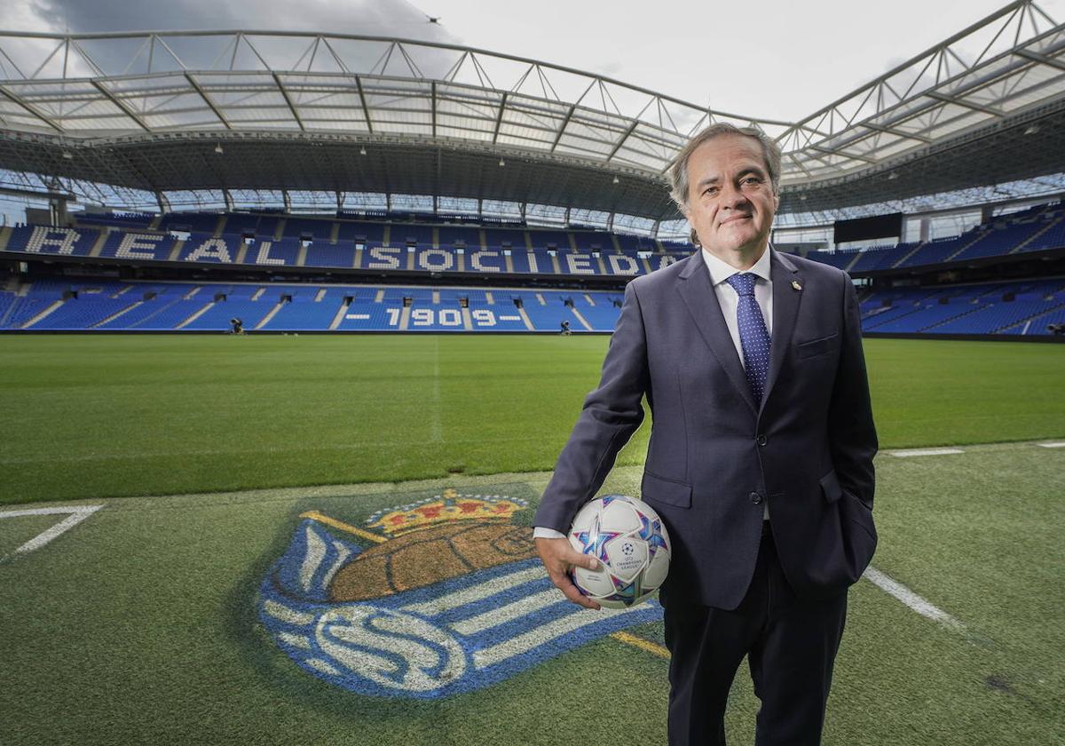Jokin Aperribay posa junto al escudo de la Real en el césped del Reale Arena con un balón de la Liga de Campeones en su mano derecha.