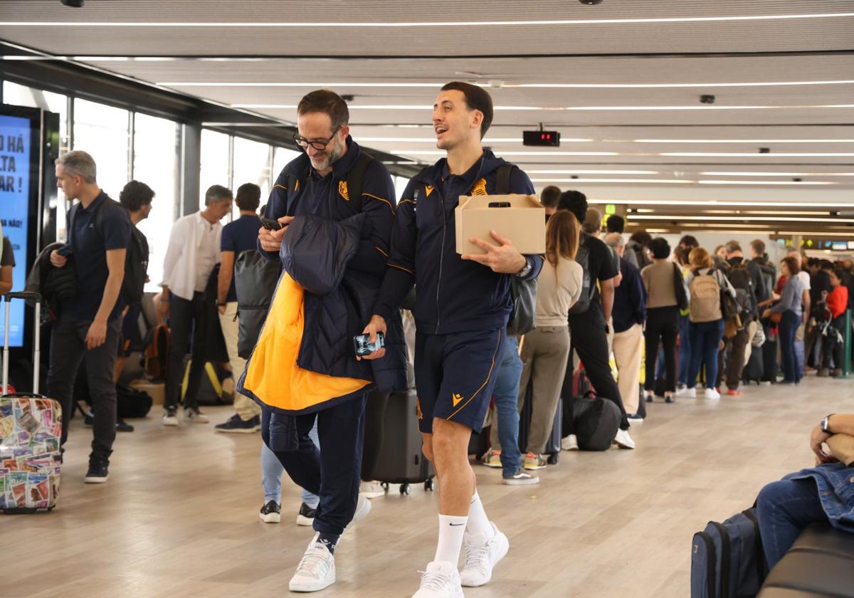 Mikel Oyarzabal, con la caja de la comida, acompañado por el fisioterapeuta Imanol Soroa, en el aeropuerto de Lisboa.