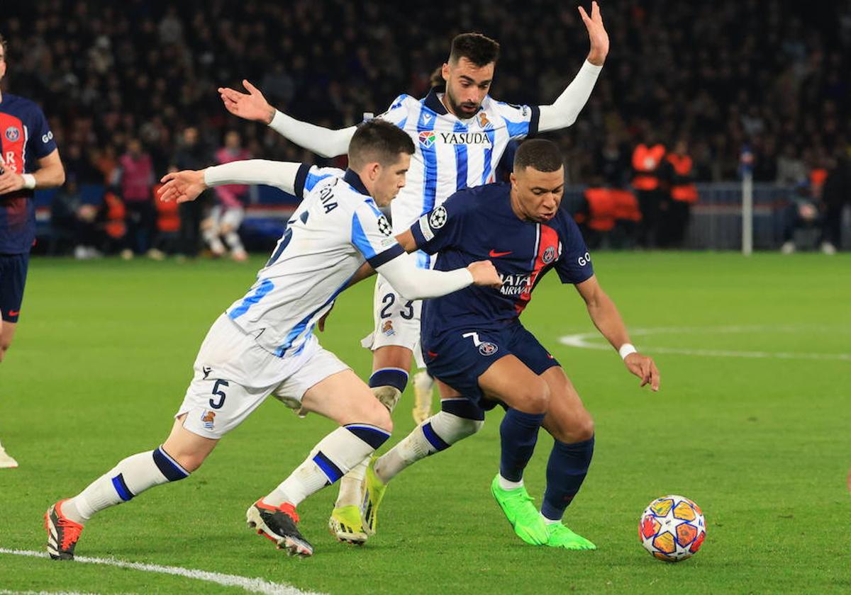 Duelo. Mbappé protege el balón ante la presión de Zubeldia y Brais, una constante en el transcurso del partido cada vez que el atacante galo tocó el cuero.