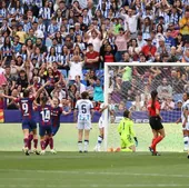 Las jugadoras del Barcelona celebran uno de los ocho goles marcados en la final disputada en La Romareda mientras las realistas se lamentan ante el fondo repleto de aficionados txuri-urdin.