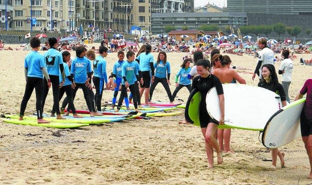 Un grupo de alumnos de surf entrenando fuera del mar de la playa de Gros antes de sumergirse en él. 