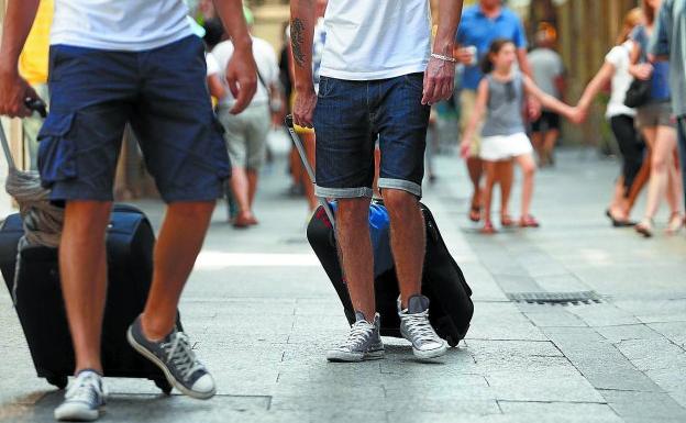 Dos turistas caminan con sus maletas por la Parte Vieja.