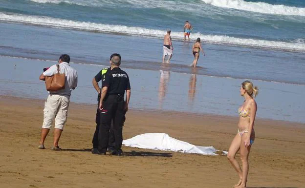 El cadáver de la bañista, junto a dos policías y el marido de la victima, de espaldas