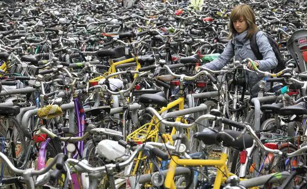Una mujer deja su bicicleta en un aparcamiento público.