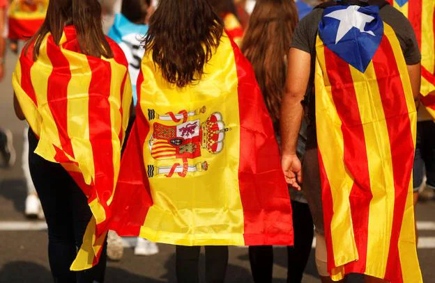 Tres jóvenes portan las tres banderas presentes en Cataluña: la senyera, la española y la estelada.