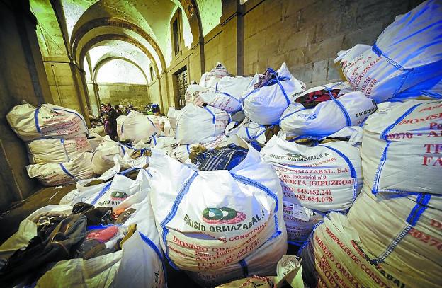 Imagen del pórtico de la iglesia San Francisco repleto de sacos de ropa donada por la gente. 