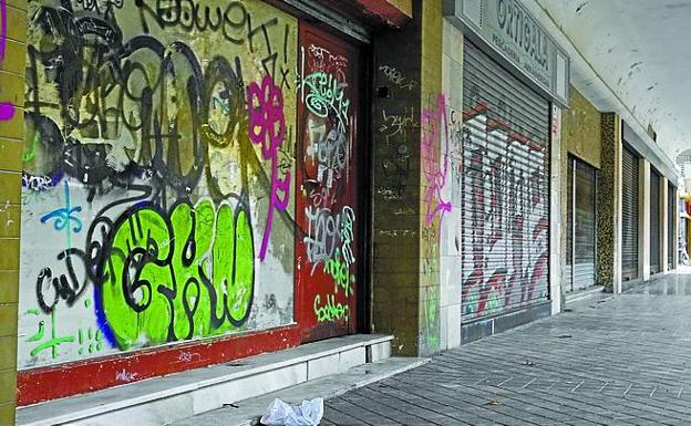 Comercios cerrados con grafitis en la plaza del Suce. 
