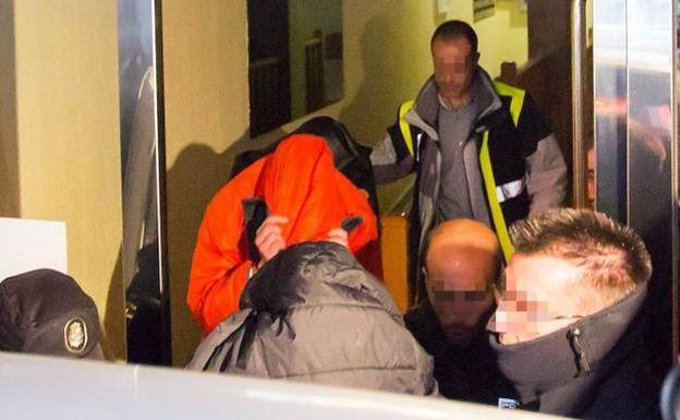 Dos de los investigados salen ocultos del piso que comparten en Aranda de Duero acompañados de policías. 
