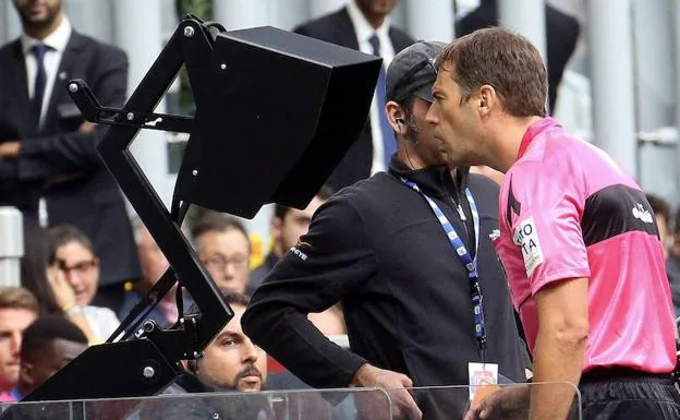 Un árbitro italiano consulta una jugada polémica durante un partido del Calcio. 