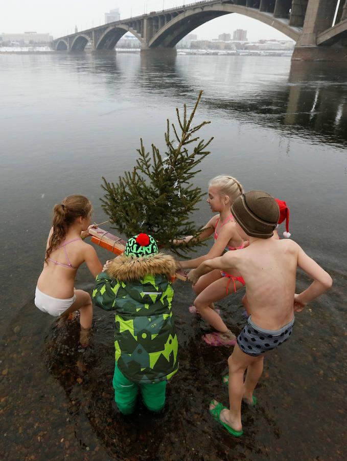 Miembros del club de nadadores de invierno Cryophile amateurs y sus hijos, acompañados por el padre Frost, el equivalente ruso de Santa Claus, se dan un baño en el río Yenisei, Rusia. Esta es su forma de celebrar la llegada de la Navidad y el Año Nuevo.