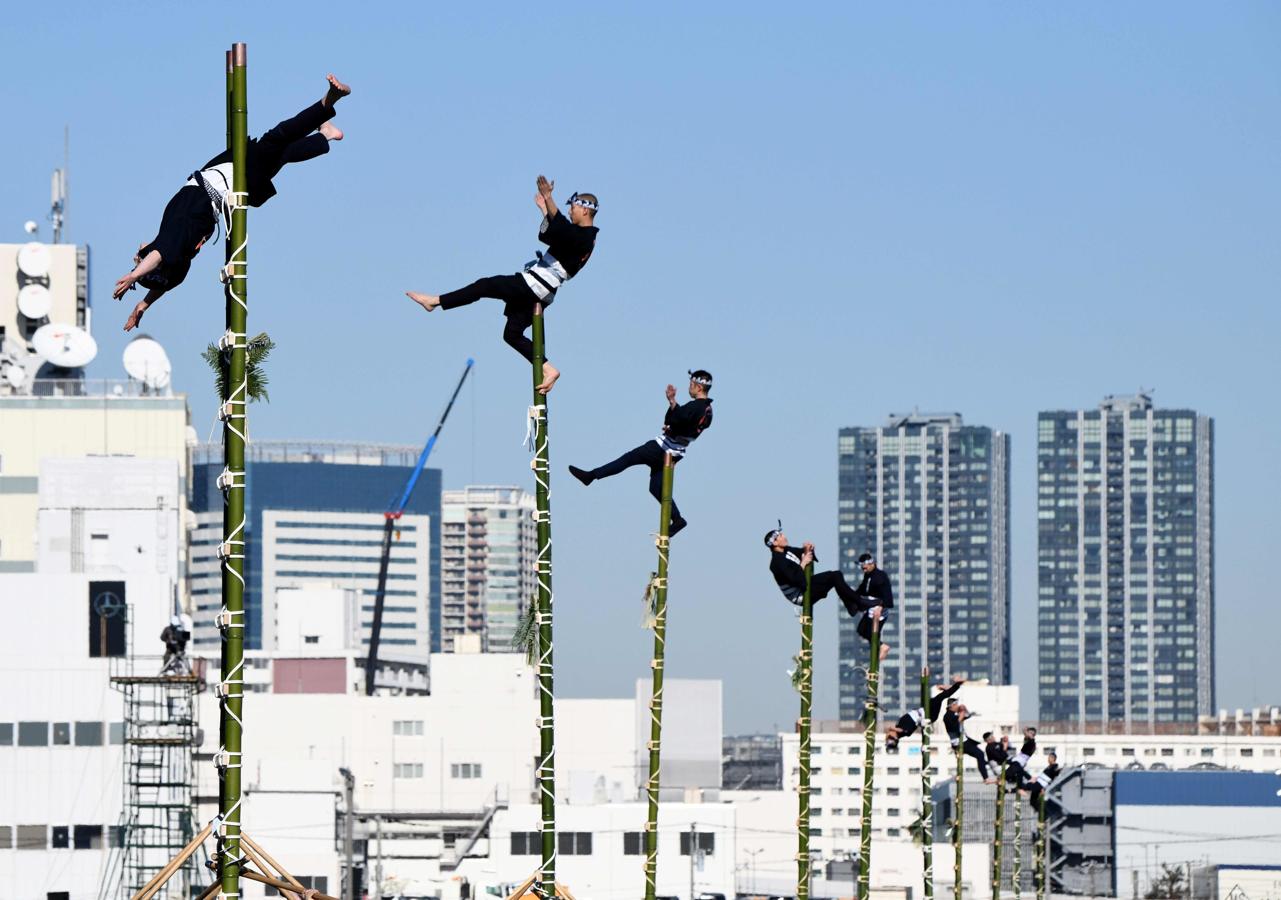 Los miembros de la Asociación de Preservación de Edo Firemanship muestran sus habilidades de equilibrio sobre escaleras de bambú durante la revisión de Fuego de Año Nuevo del Departamento de Bomberos de Tokio