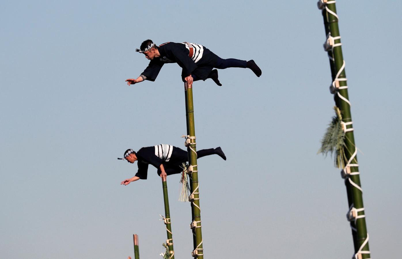 Los miembros de la Asociación de Preservación de Edo Firemanship muestran sus habilidades de equilibrio sobre escaleras de bambú durante la revisión de Fuego de Año Nuevo del Departamento de Bomberos de Tokio