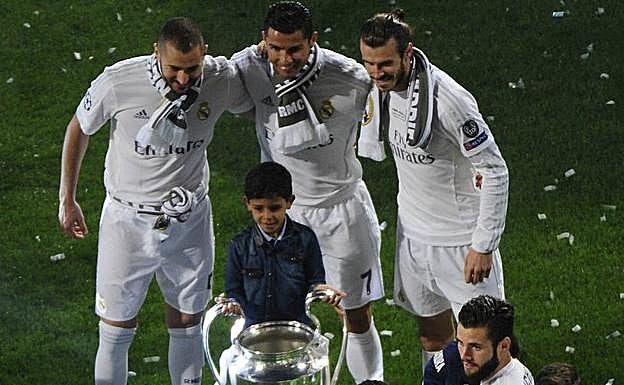 Karim Benzema, Cristiano Ronaldo y Gareth Bale posan junto al hijo del astro portugués con el trofeo de la Champions. 