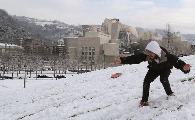 Un joven disfruta de la nieve junto al Guggenheim de Bilbao.